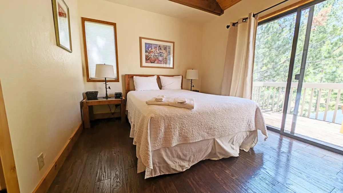 A cozy bedroom featuring a comfortable bed, window with natural light, tasteful artwork, and matching nightstands with lamps. The room feels intimate yet open, offering guests a restful space to relax and recharge.